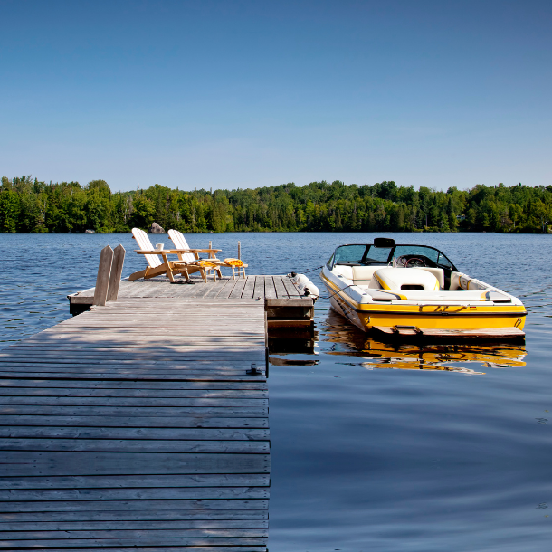 boat in the water on a lake next to a dock with chairs in the summer