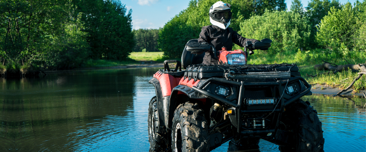 Person riding ATV through a puddle.
